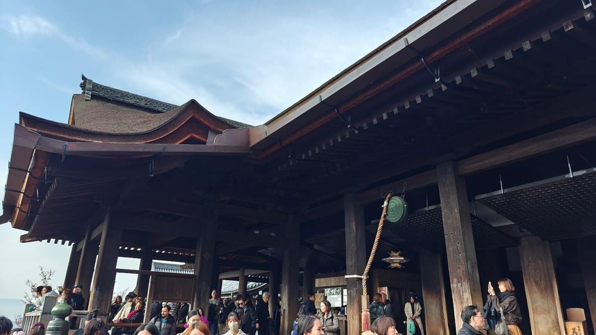 Crowd at traditional wooden temple under clear sky