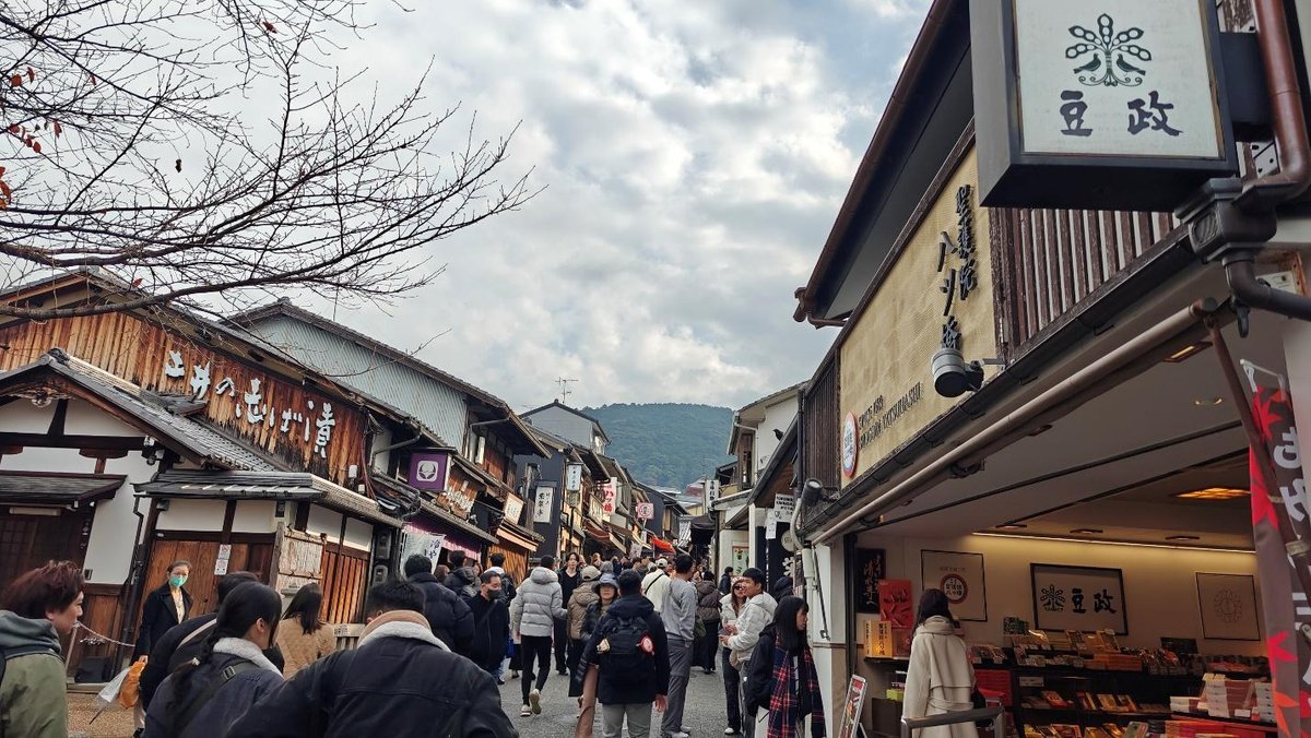 Crowded Japanese street with shops and mountains in background