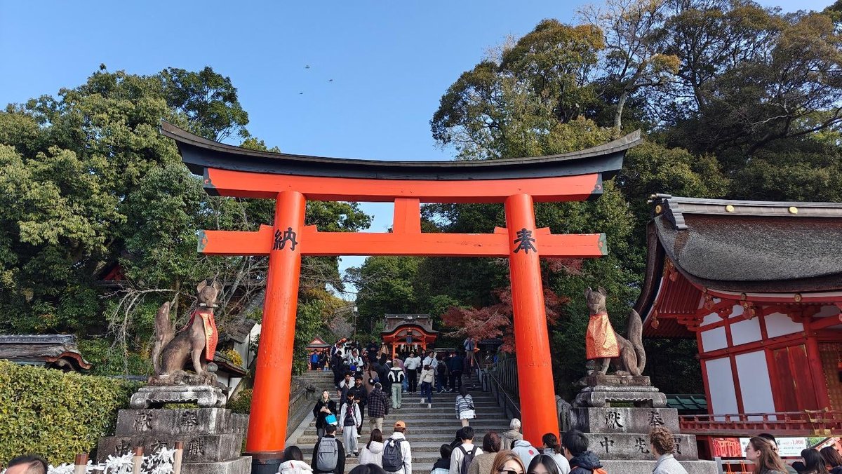 Crowded shrine entry under large red torii gate, Kyoto