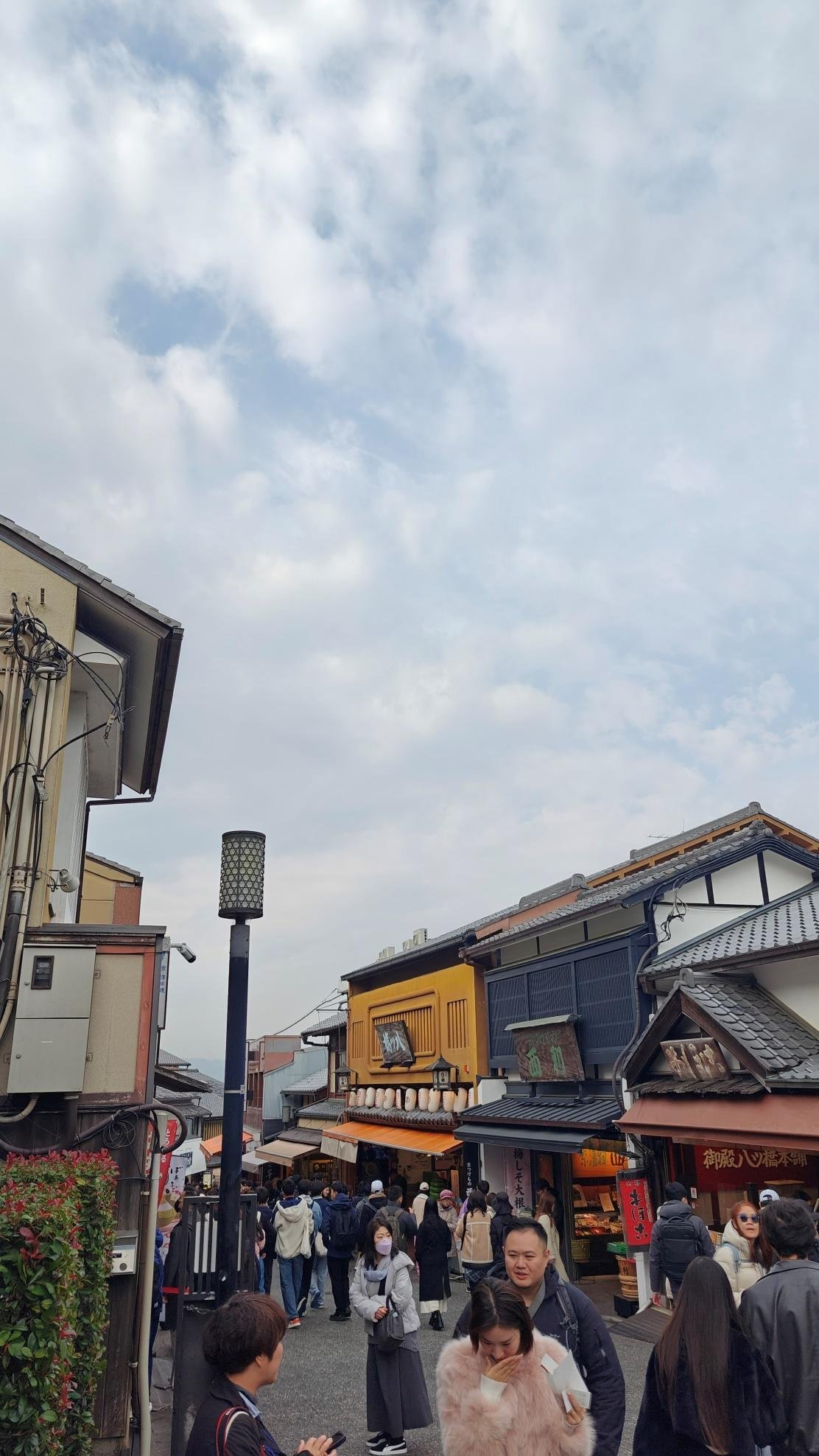 Crowded street with traditional Japanese shops under cloudy sky