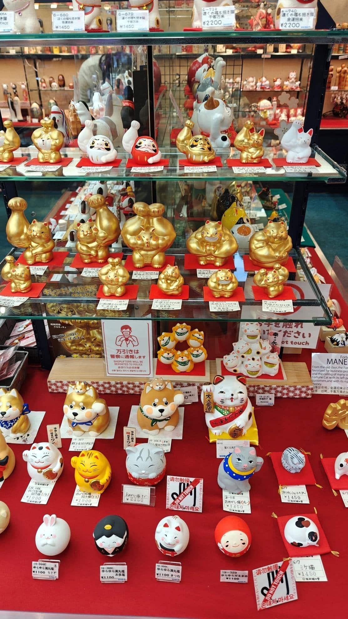 Display of colorful lucky cat figurines in a storefront.