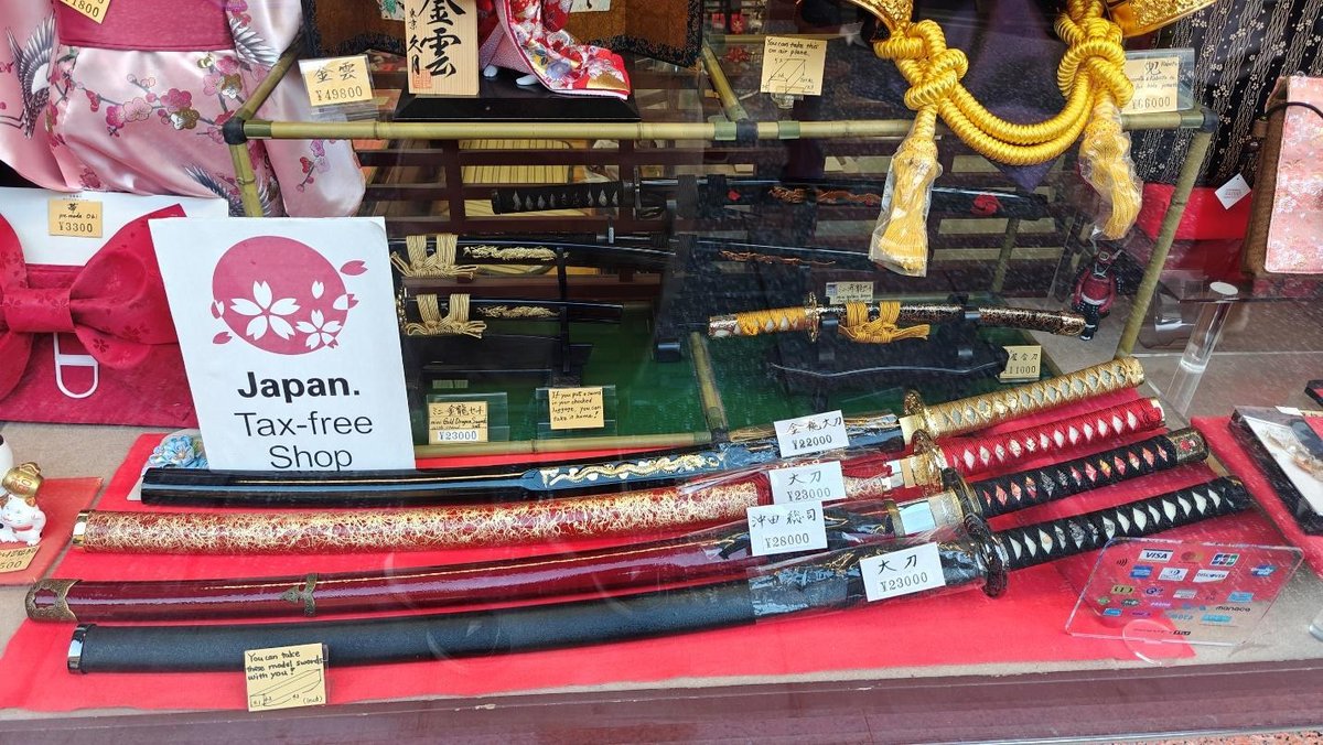 Display of ornate Japanese swords in a tax-free shop window