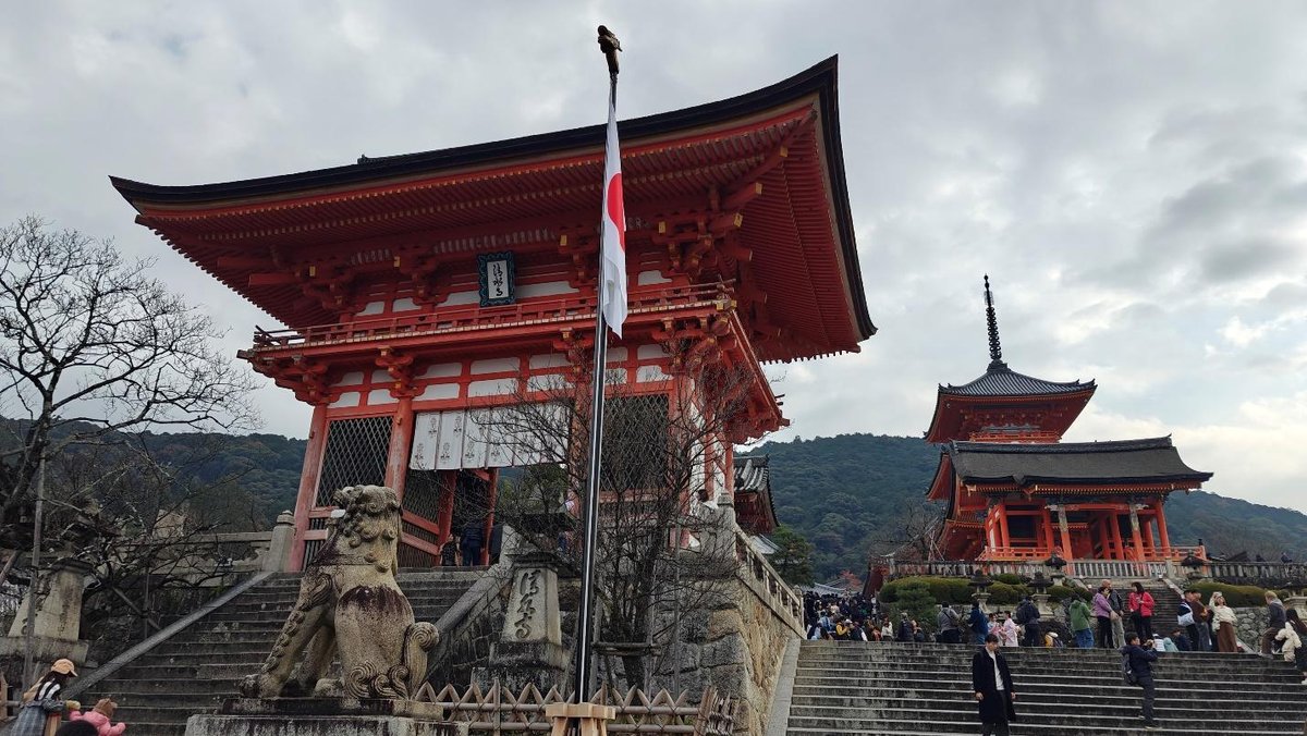 Historic red temple with pagoda and visitors on cloudy day