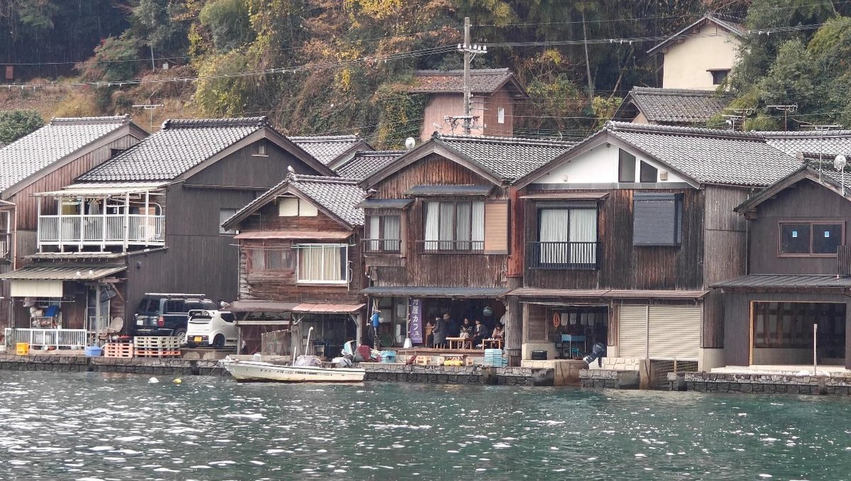Historic wooden houses by a calm waterfront with lush greenery
