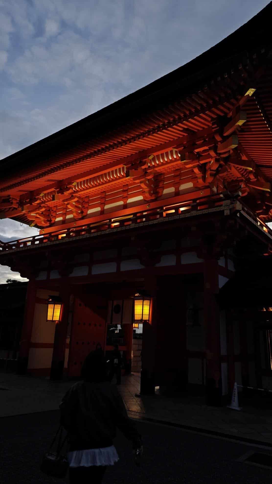 Illuminated traditional gate at dusk, person walking