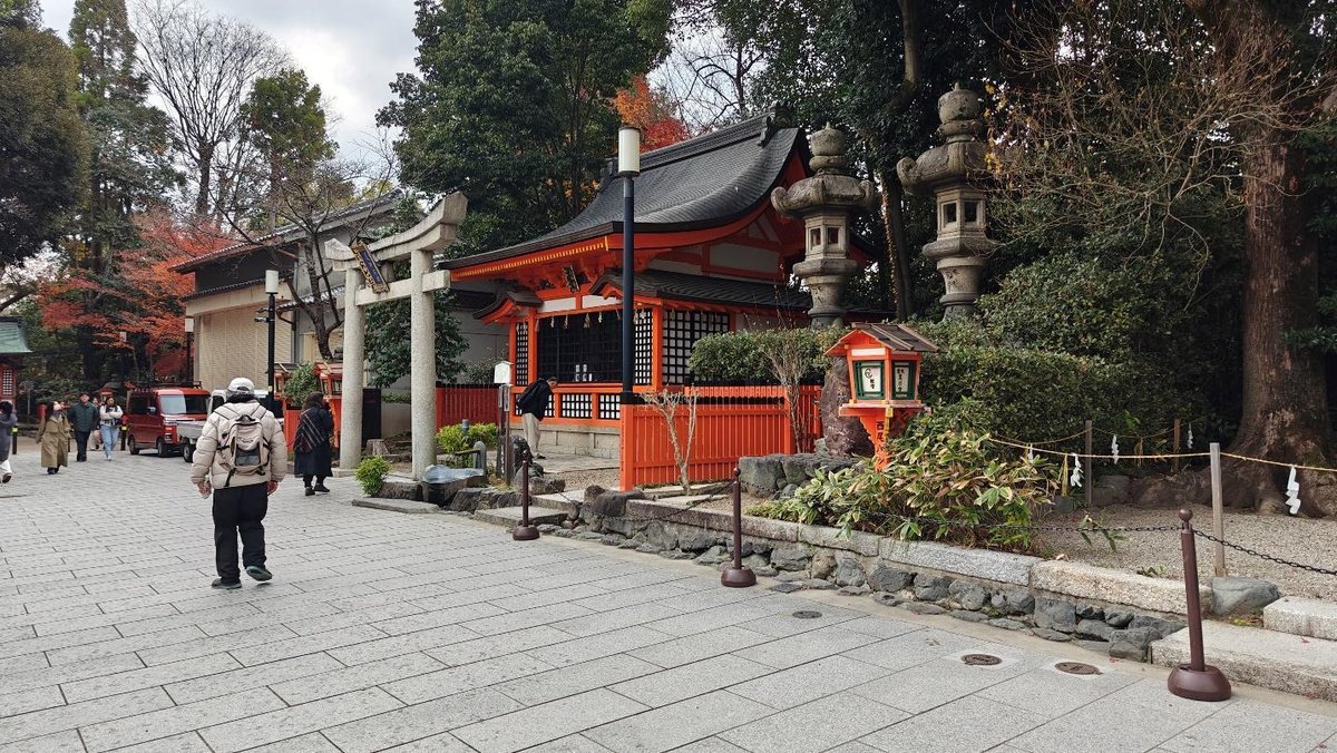 Japanese shrine with red accents and visitors walking