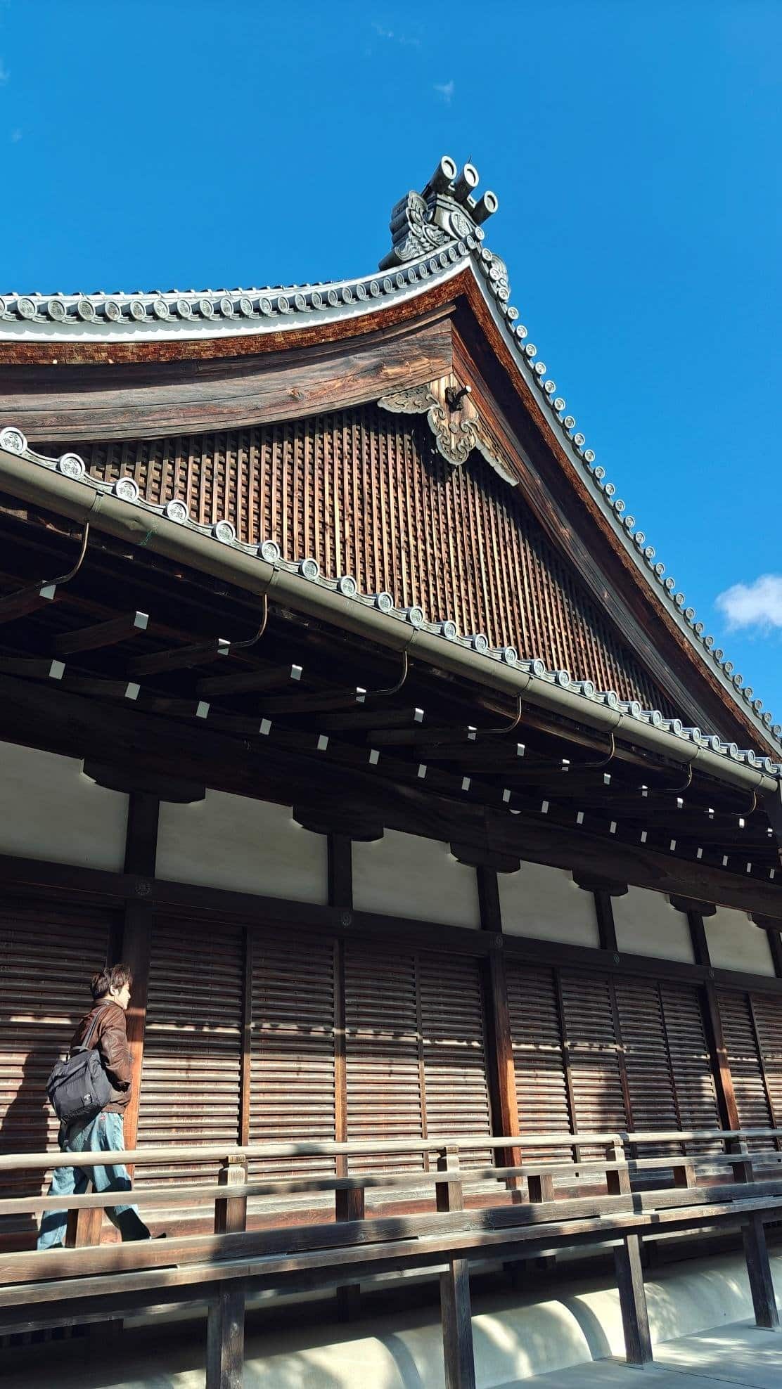 Man walking past traditional wooden Japanese architecture