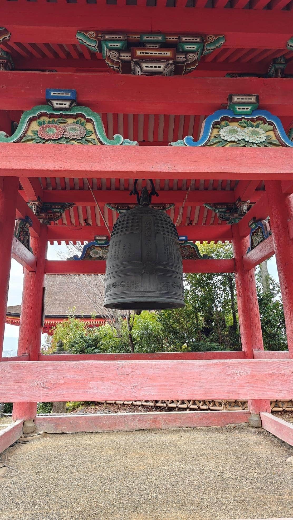 Ornate Japanese temple bell with red wooden structure