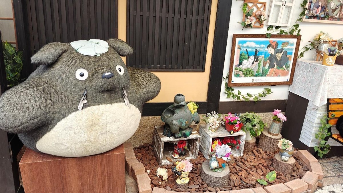 Outdoor anime-themed garden display with plush toys and flowers