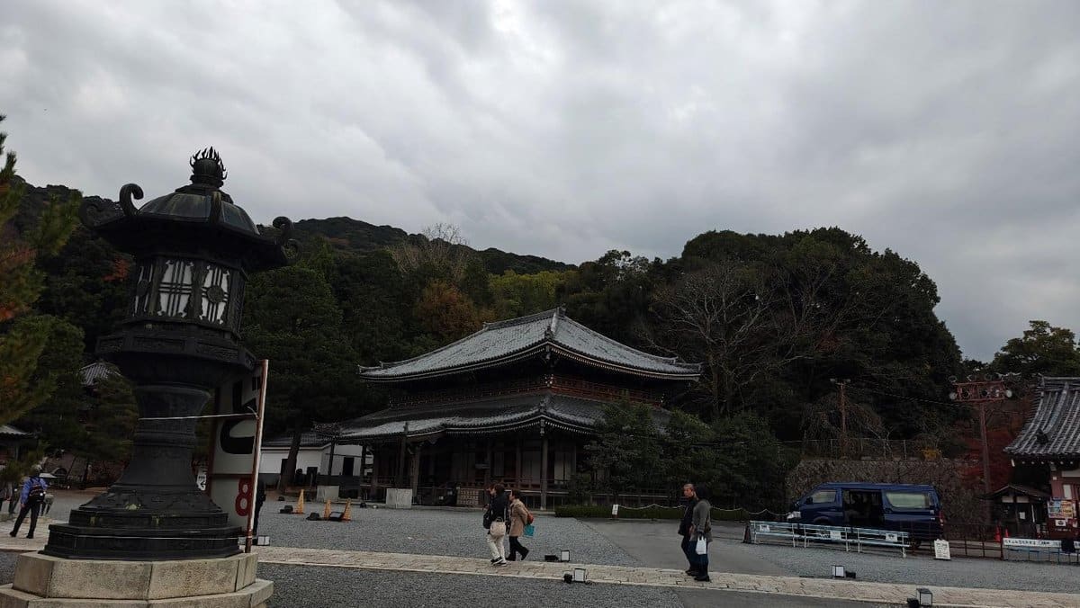 Pagoda and lantern against cloudy sky and forested hills
