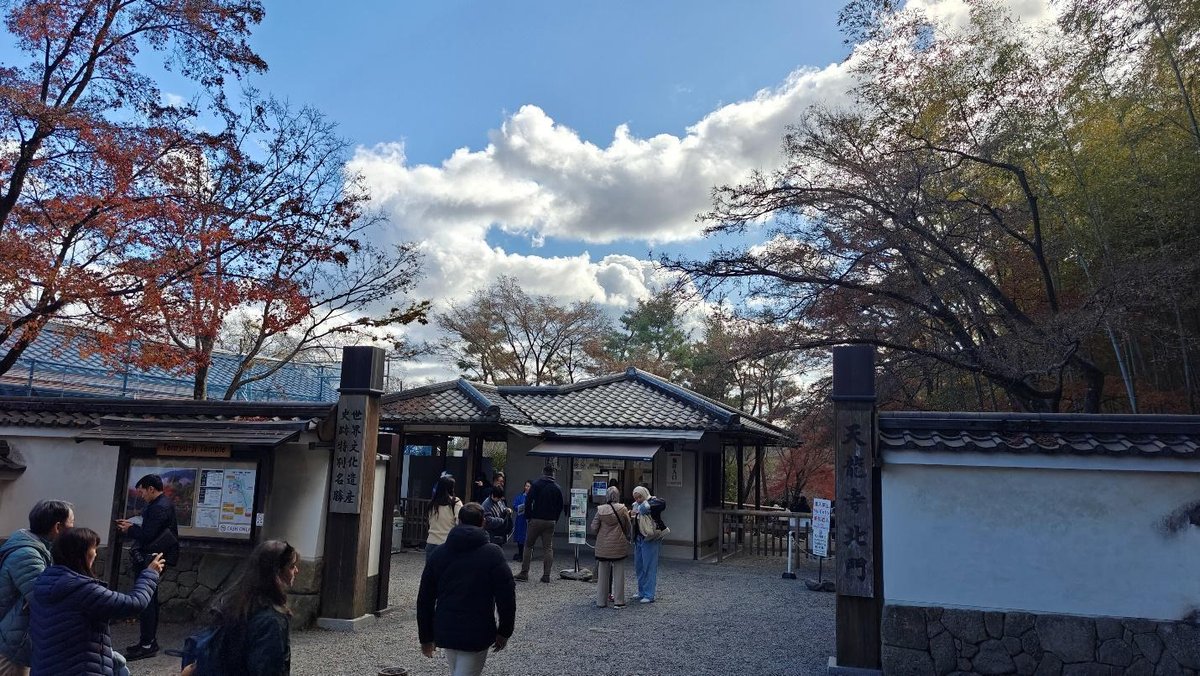 People at temple gate with autumn trees and clouds