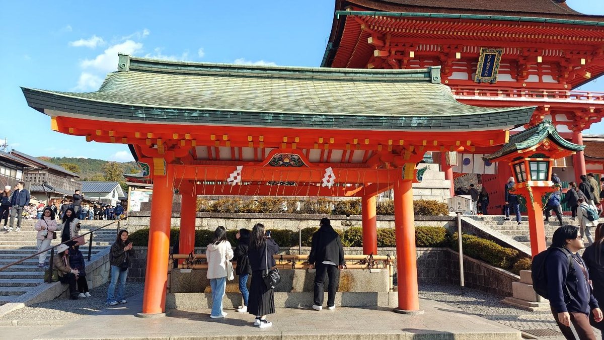 People at traditional shrine with red pillars, clear sky