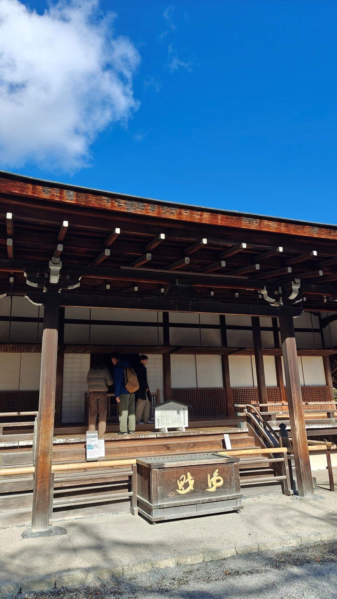 People at traditional wooden building under blue sky