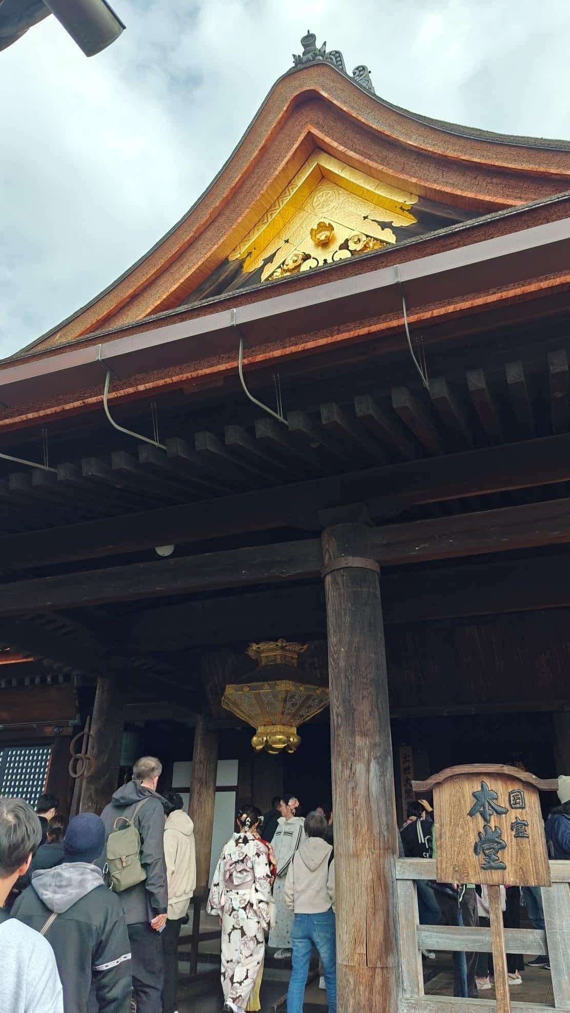 People entering traditional Japanese temple, ornate roof details