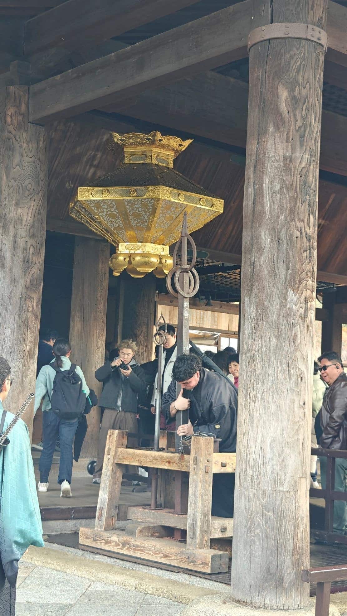 People exploring temple with ornate golden lantern