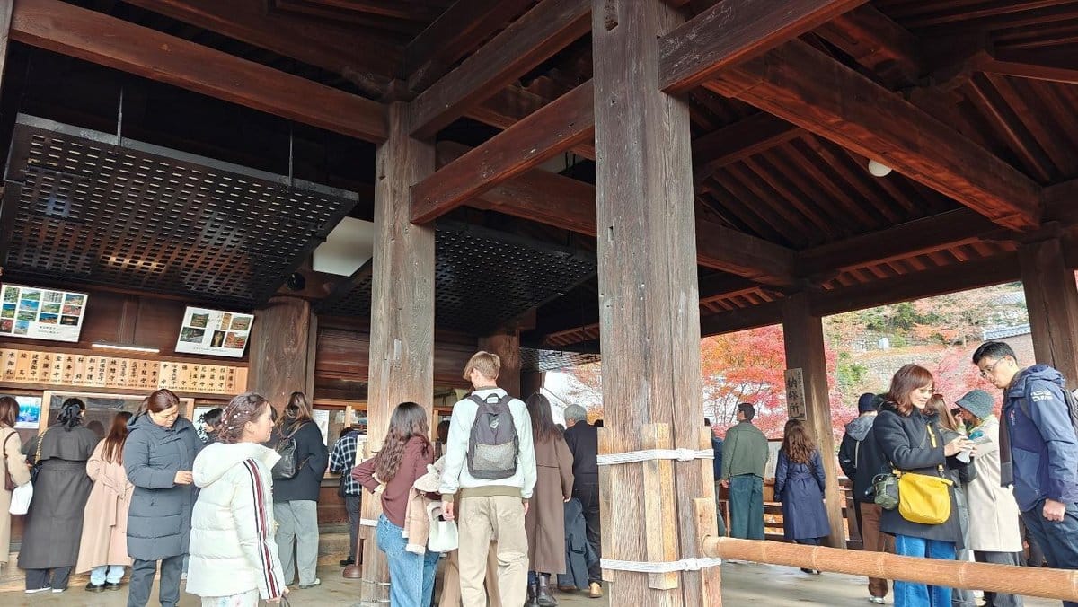People gathered under wooden pavilion with autumn foliage