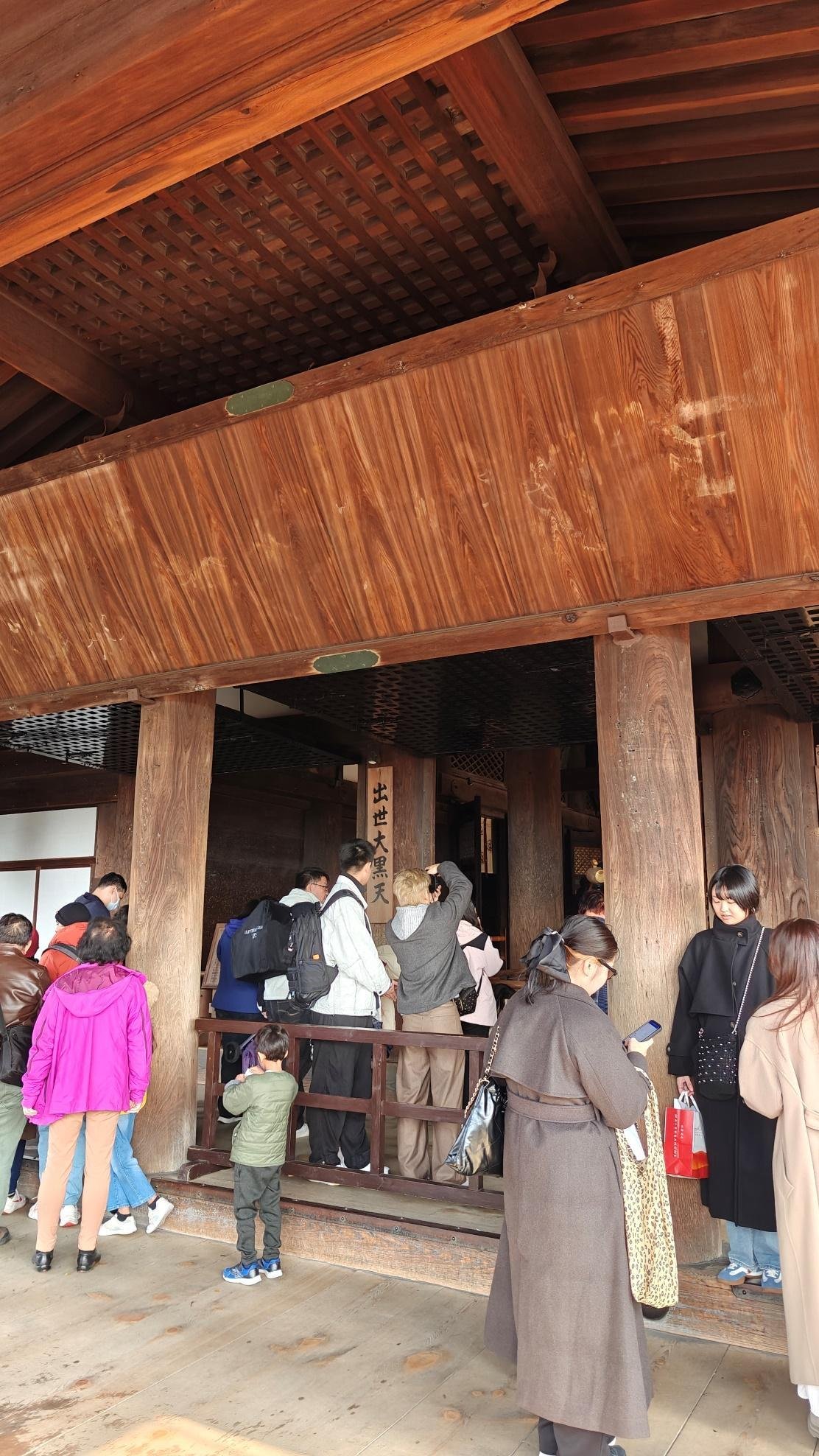 People queue outside a wooden temple entrance