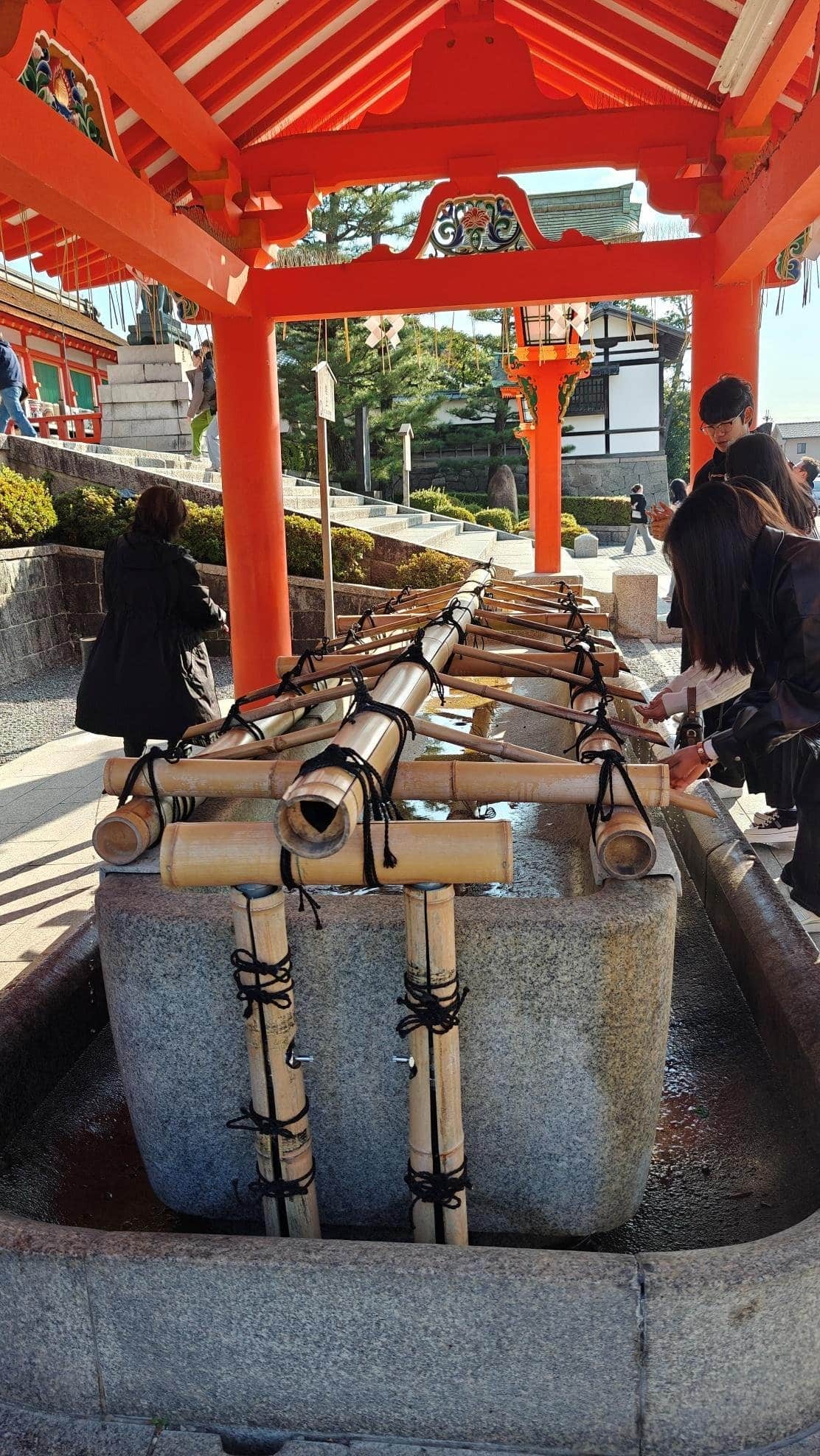 People using a traditional Japanese water purification basin