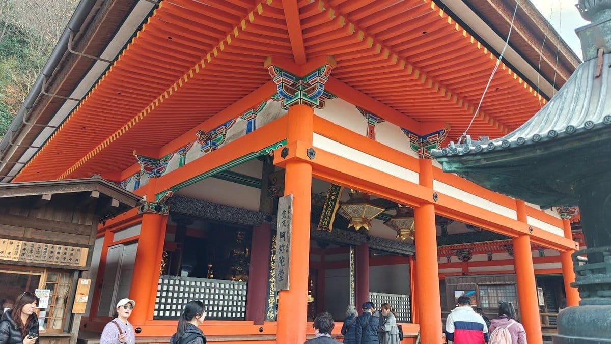 People visiting vibrant orange temple with intricate roof design