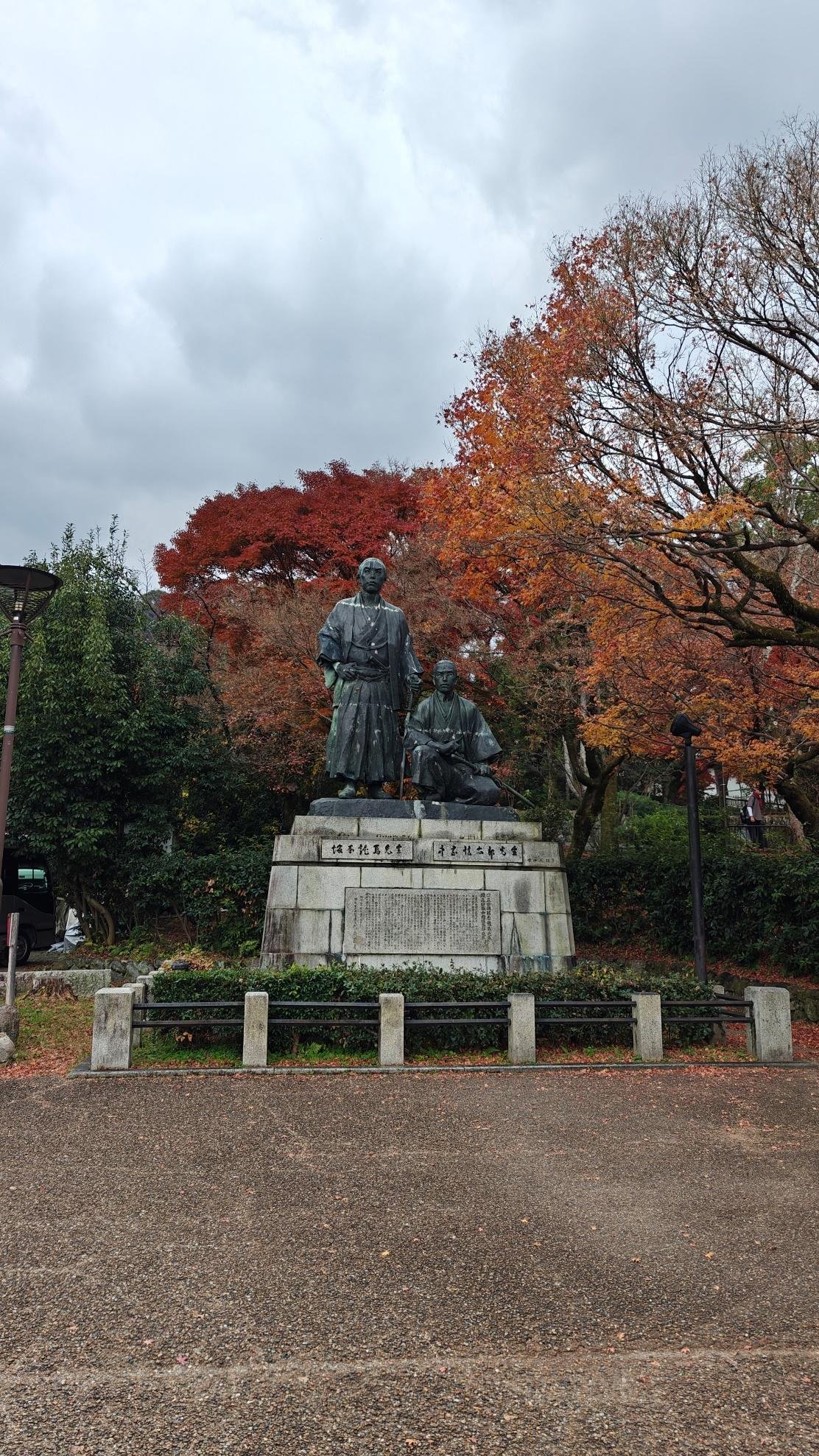 Statue surrounded by autumn trees and cloudy sky