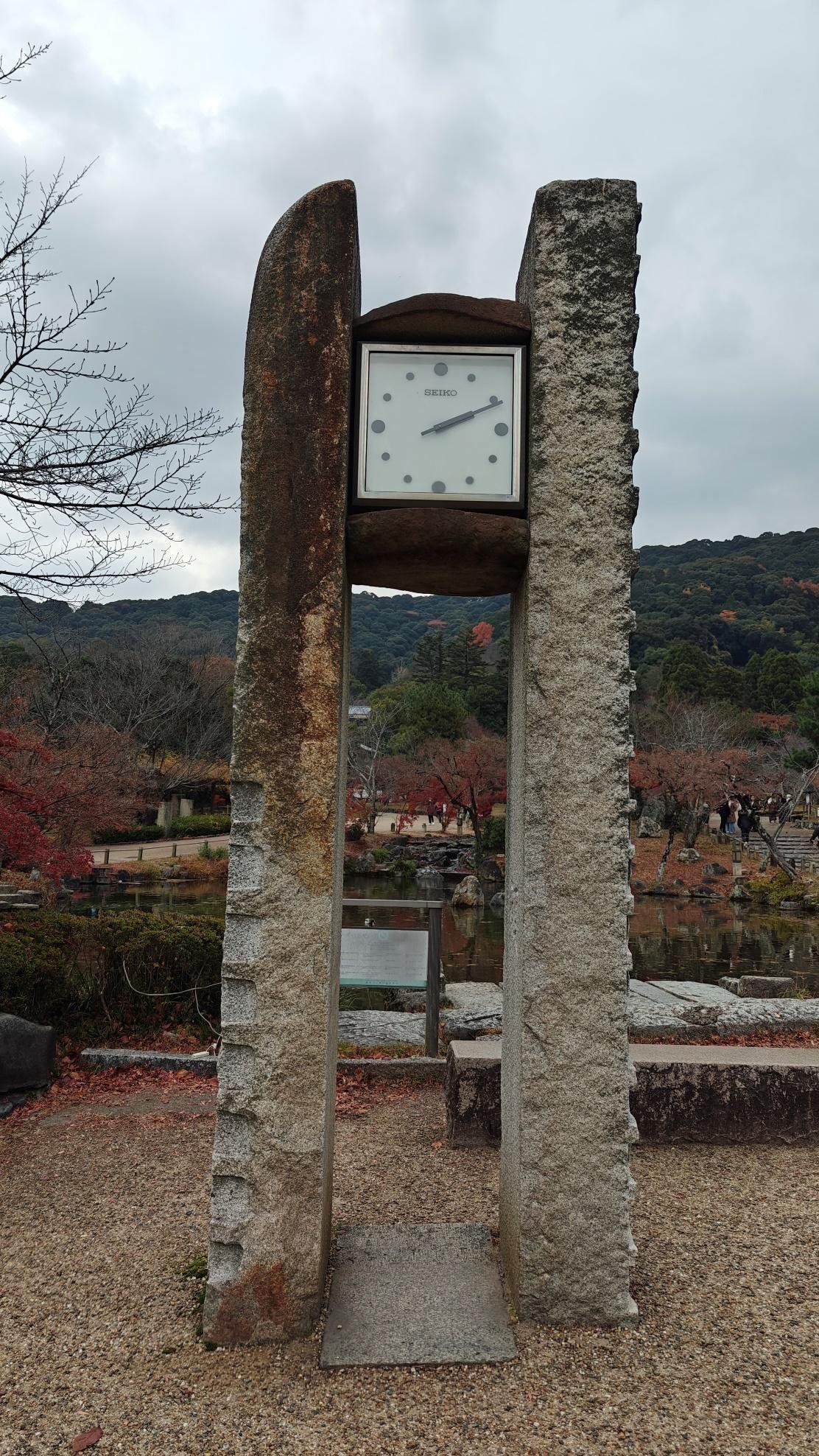 Stone monument with clock in scenic park setting