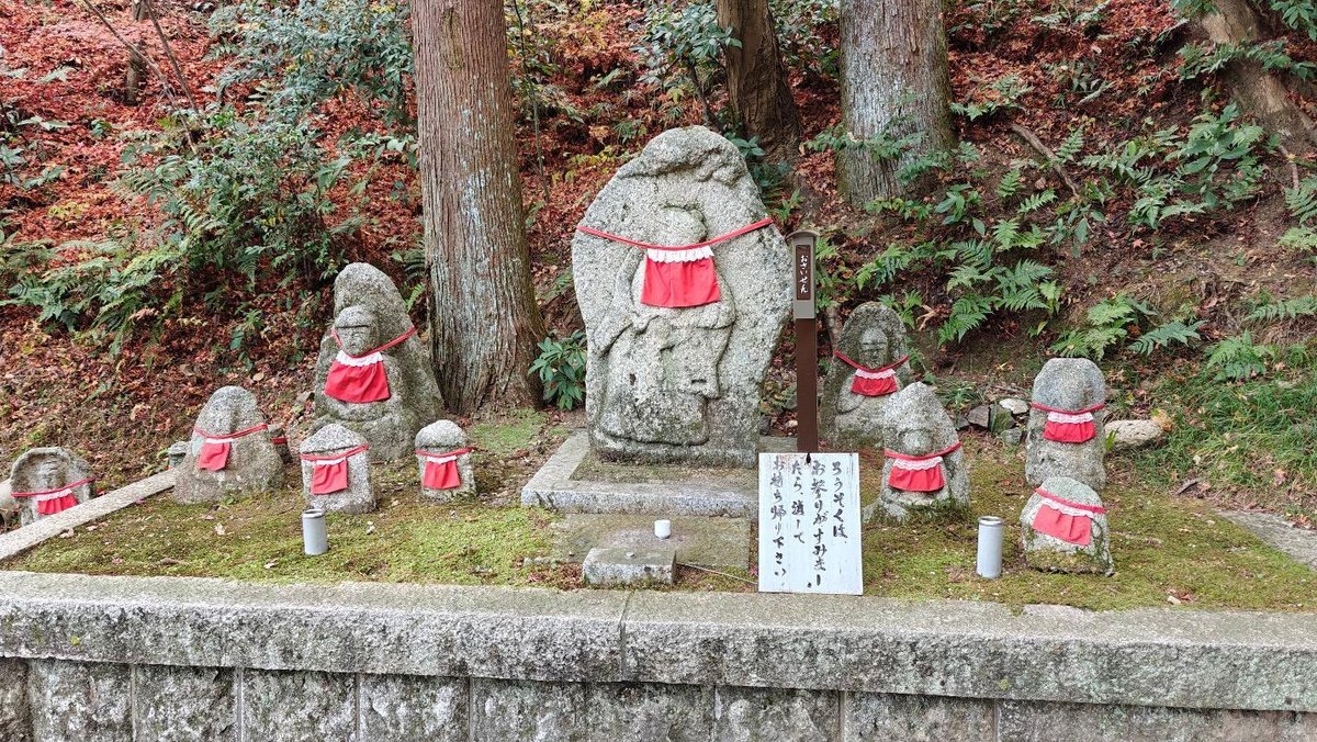 Stone statues with red bibs in forest setting