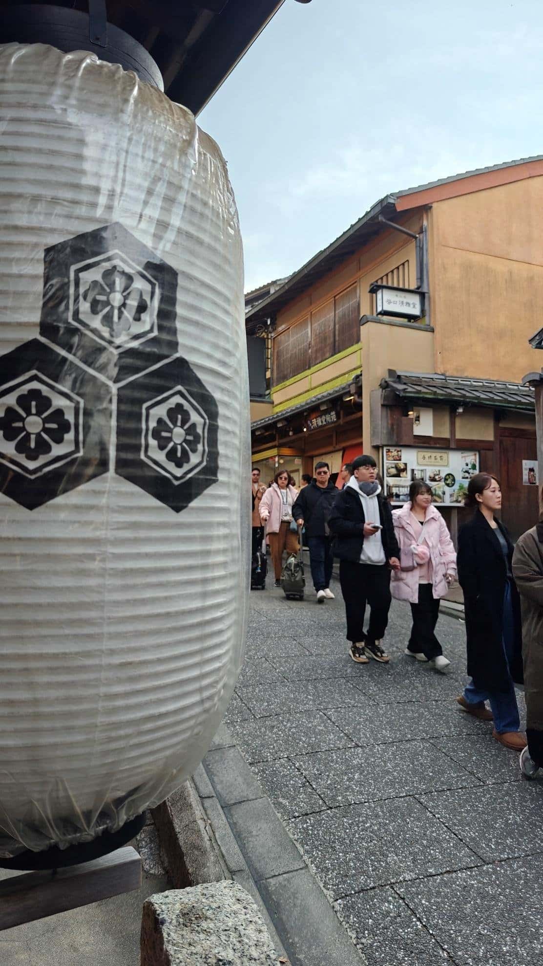 Street with large lantern and people walking by traditional buildings