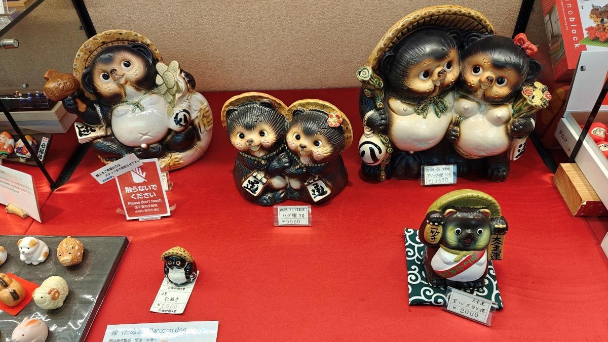 Tanuki figurines on red display with price tags