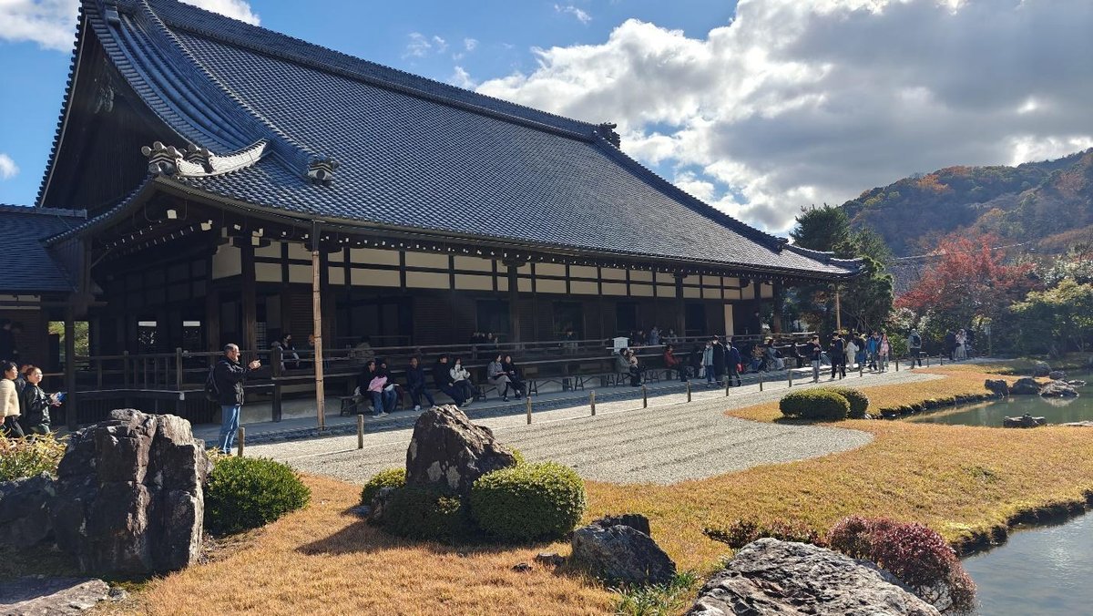 Temple with autumn garden and visitors under blue sky