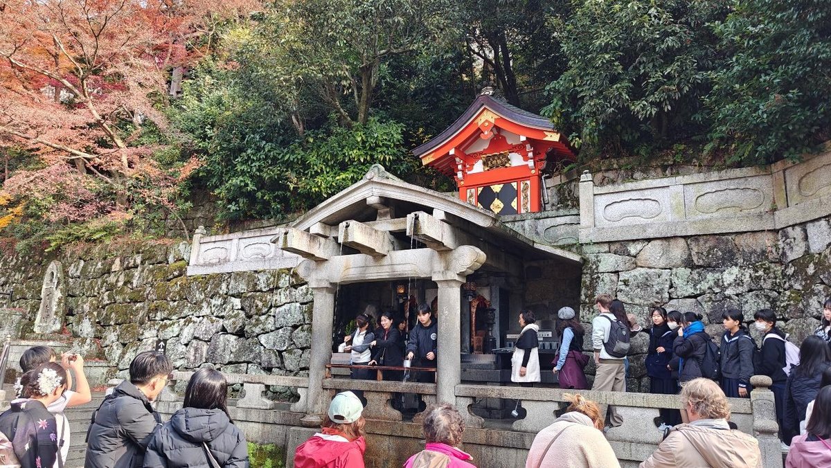 Tourists at a traditional Japanese shrine with autumn trees
