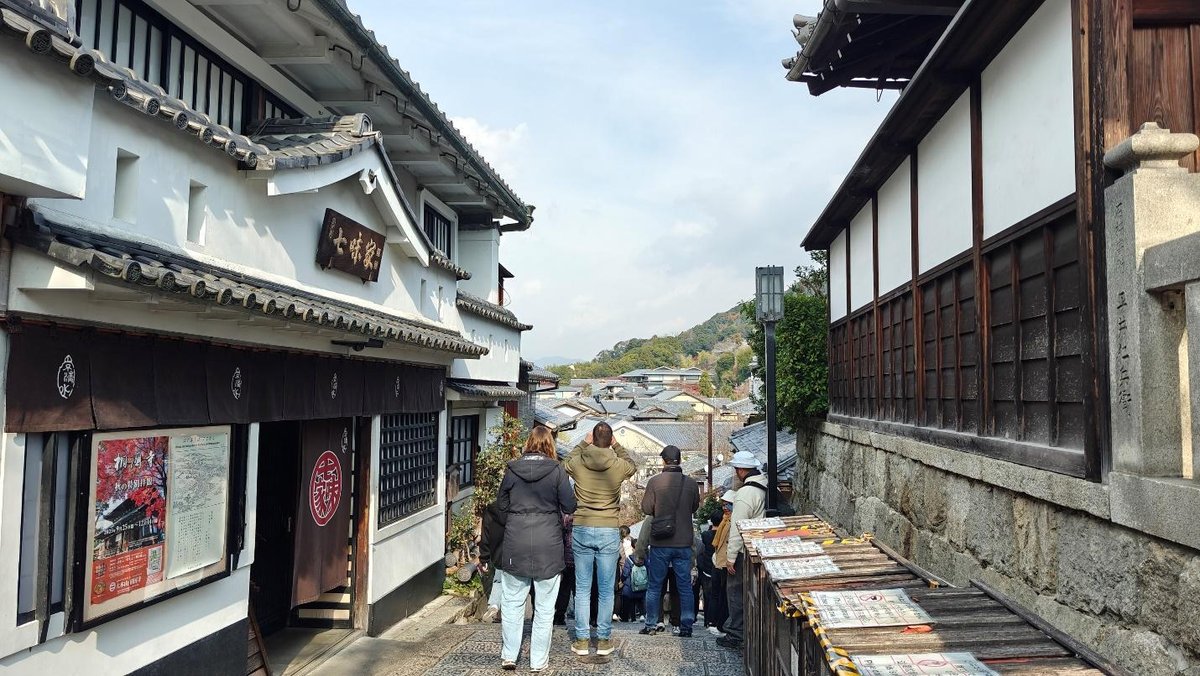 Tourists exploring traditional Japanese street with hillside view