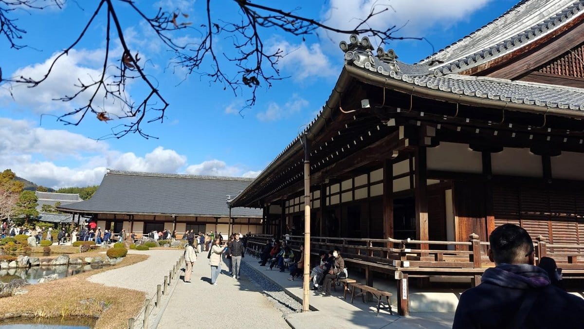 Traditional Japanese building with visitors exploring gardens