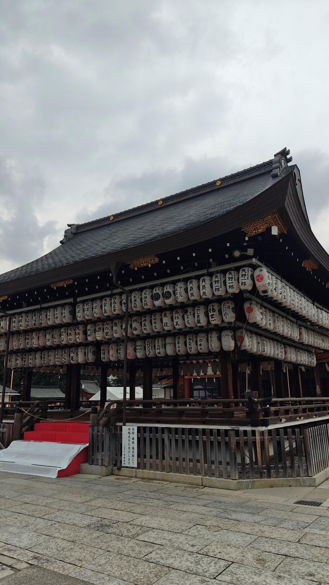 Traditional Japanese temple with hanging lanterns under cloudy sky