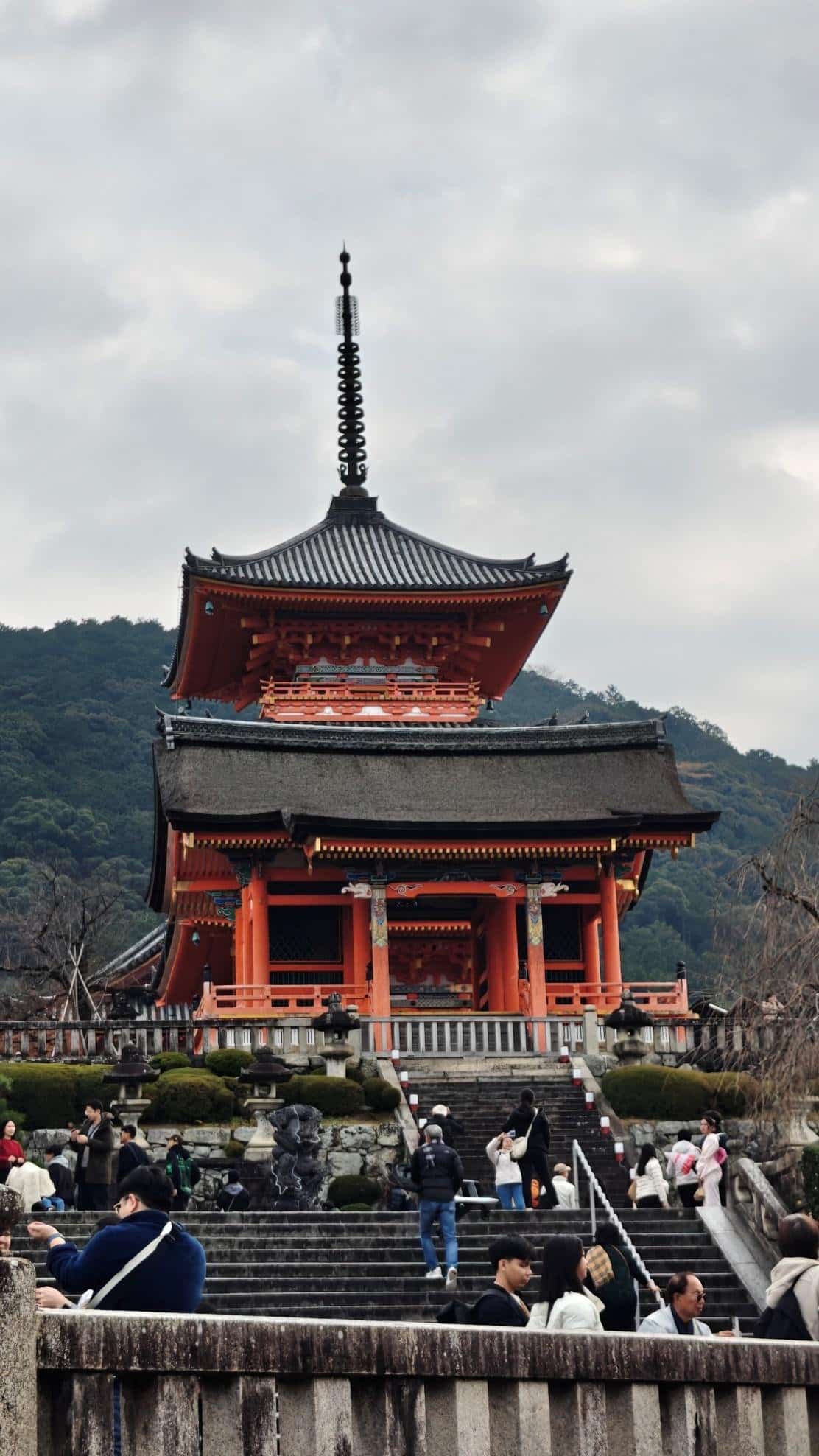 Traditional Japanese temple with tourists and cloudy sky