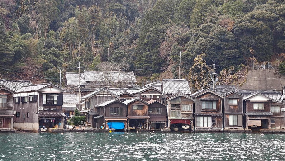 Traditional waterfront houses by forested hillside