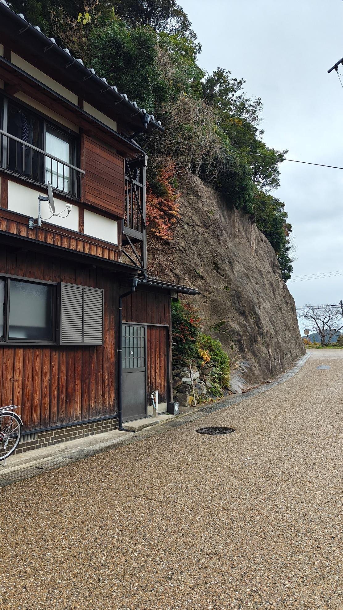 Traditional wooden house by rocky cliff under cloudy sky