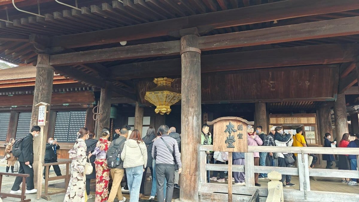 Visitors at a traditional temple entrance with wooden columns