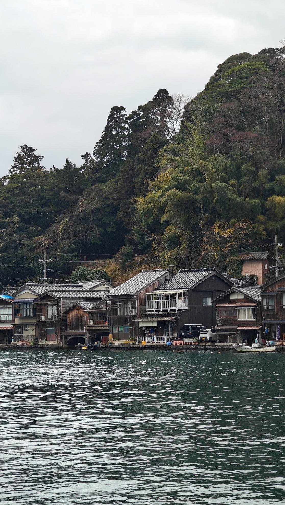Wooden houses by a lush hill and calm waters