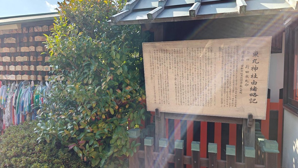 Wooden sign with Japanese text beside lush green foliage