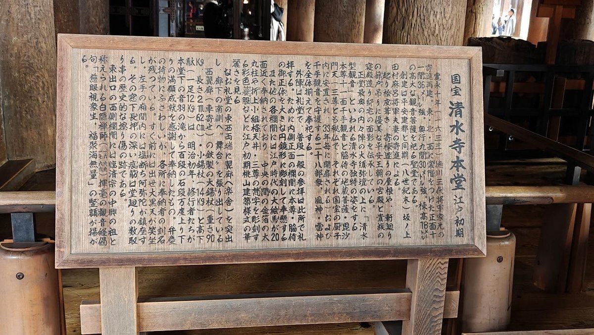Wooden sign with Japanese text in a temple setting