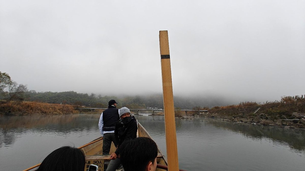 Boat journey on misty river with foggy hills in background