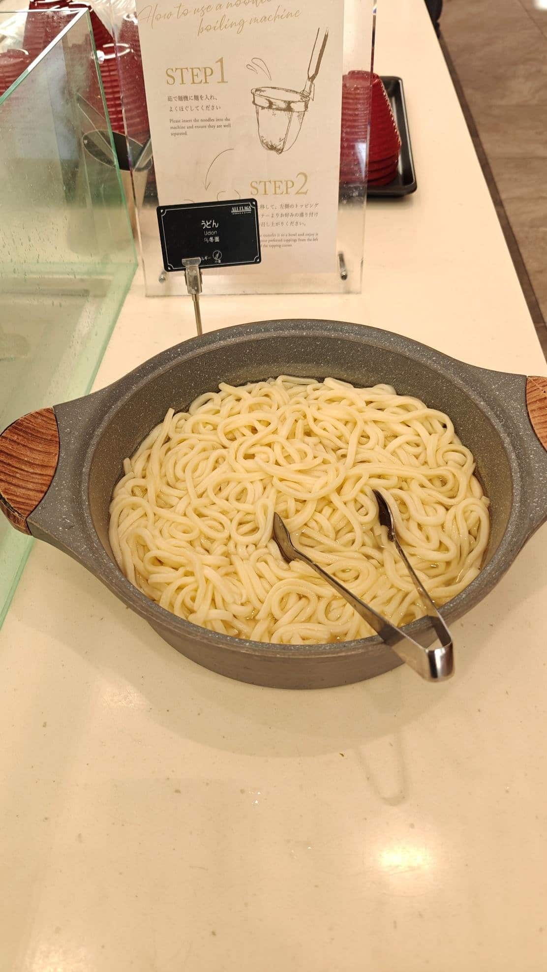 Bowl of udon noodles with tongs