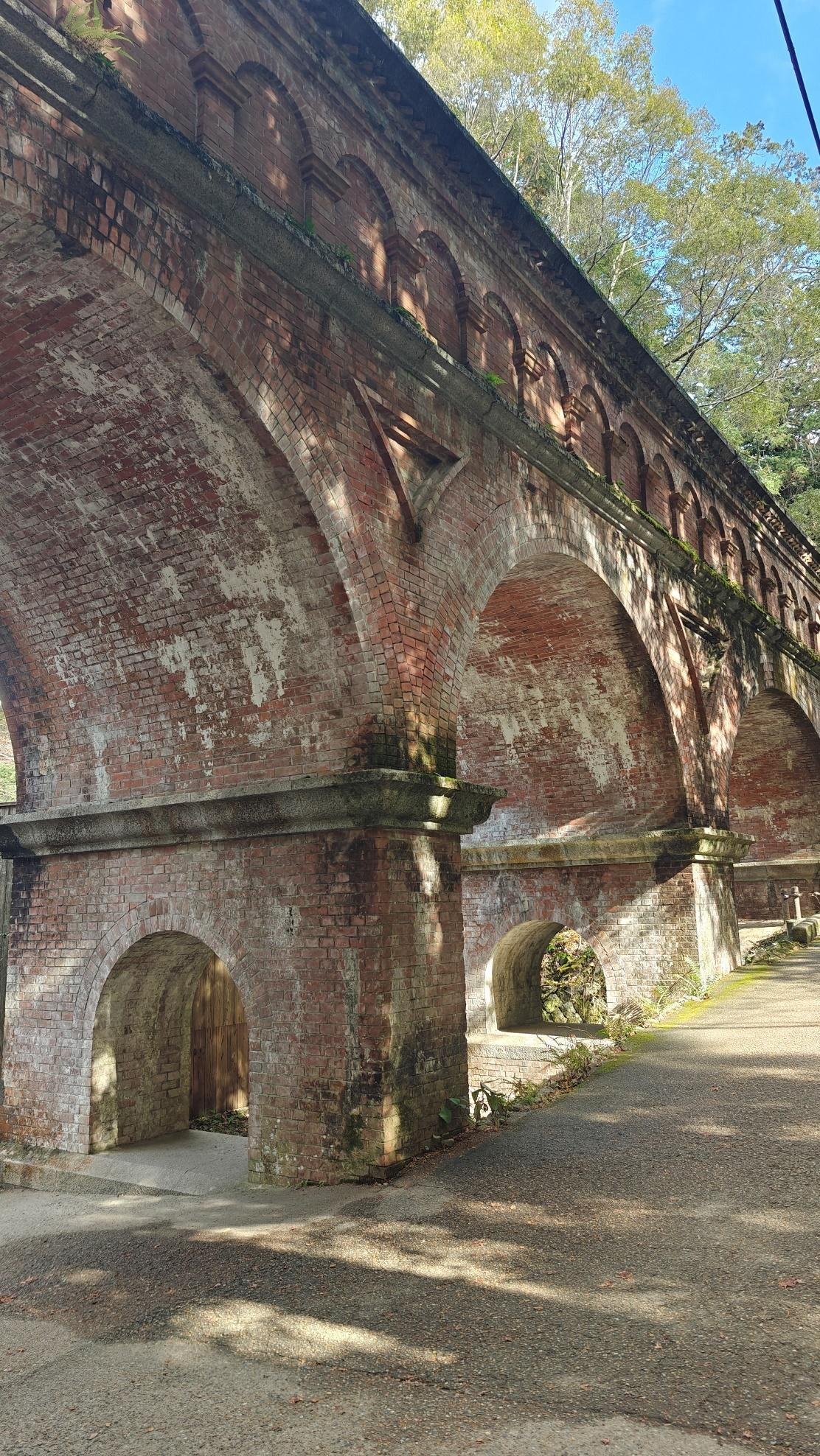 Brick aqueduct with arches and foliage in sunlight