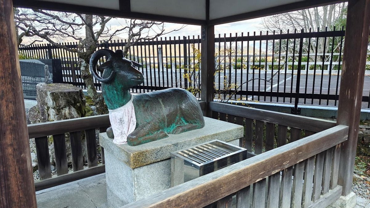 Bronze goat statue inside a wooden shelter