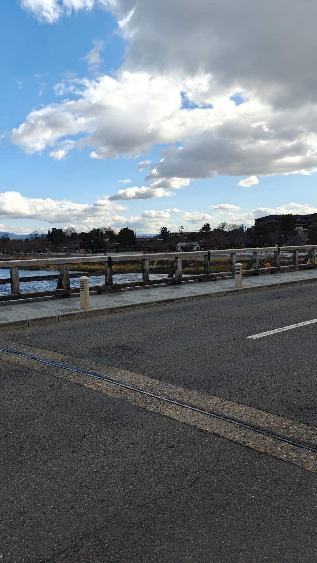 Cloudy sky over a riverside pathway and bridge