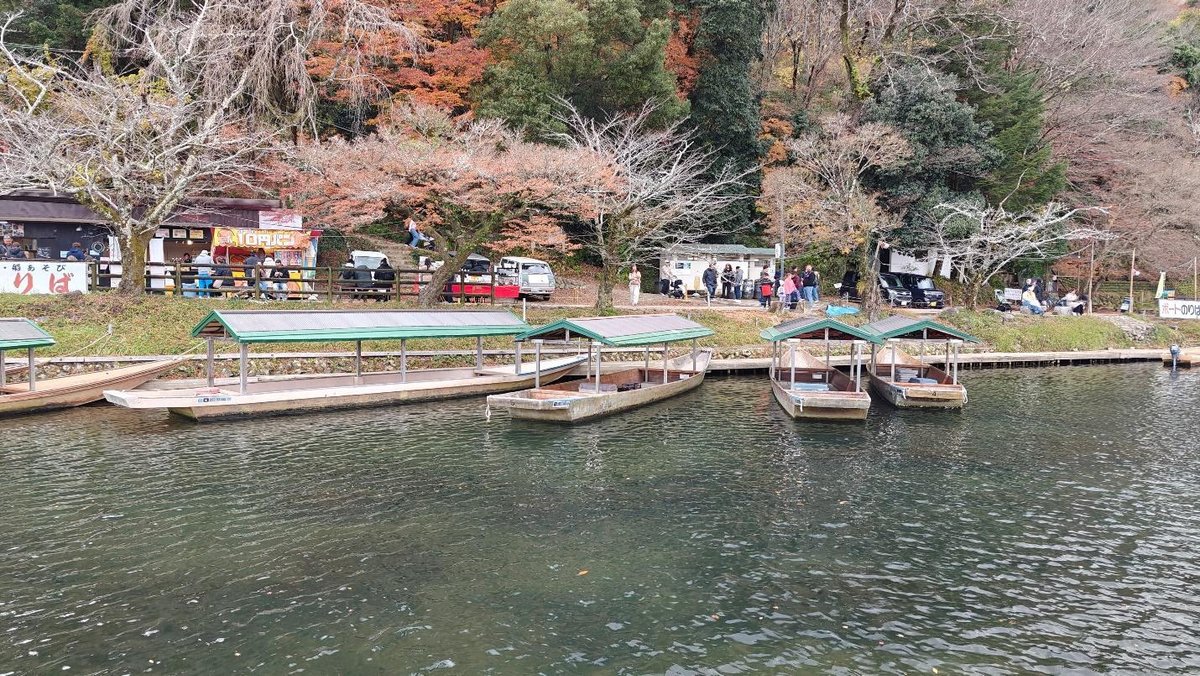 Docked wooden boats near autumn trees and food stalls