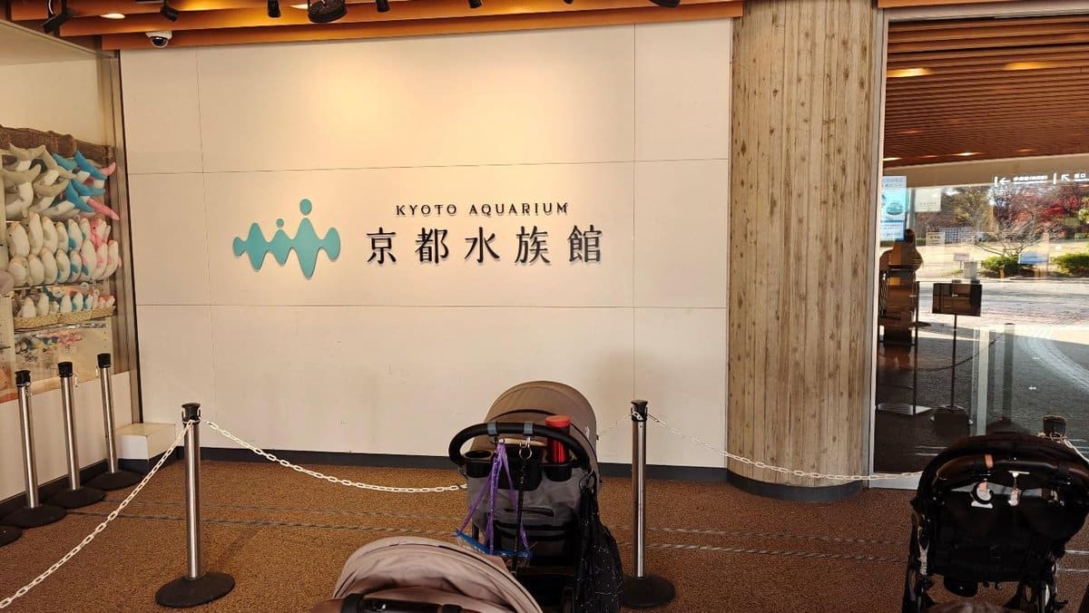 Entrance sign of Kyoto Aquarium with strollers in foreground