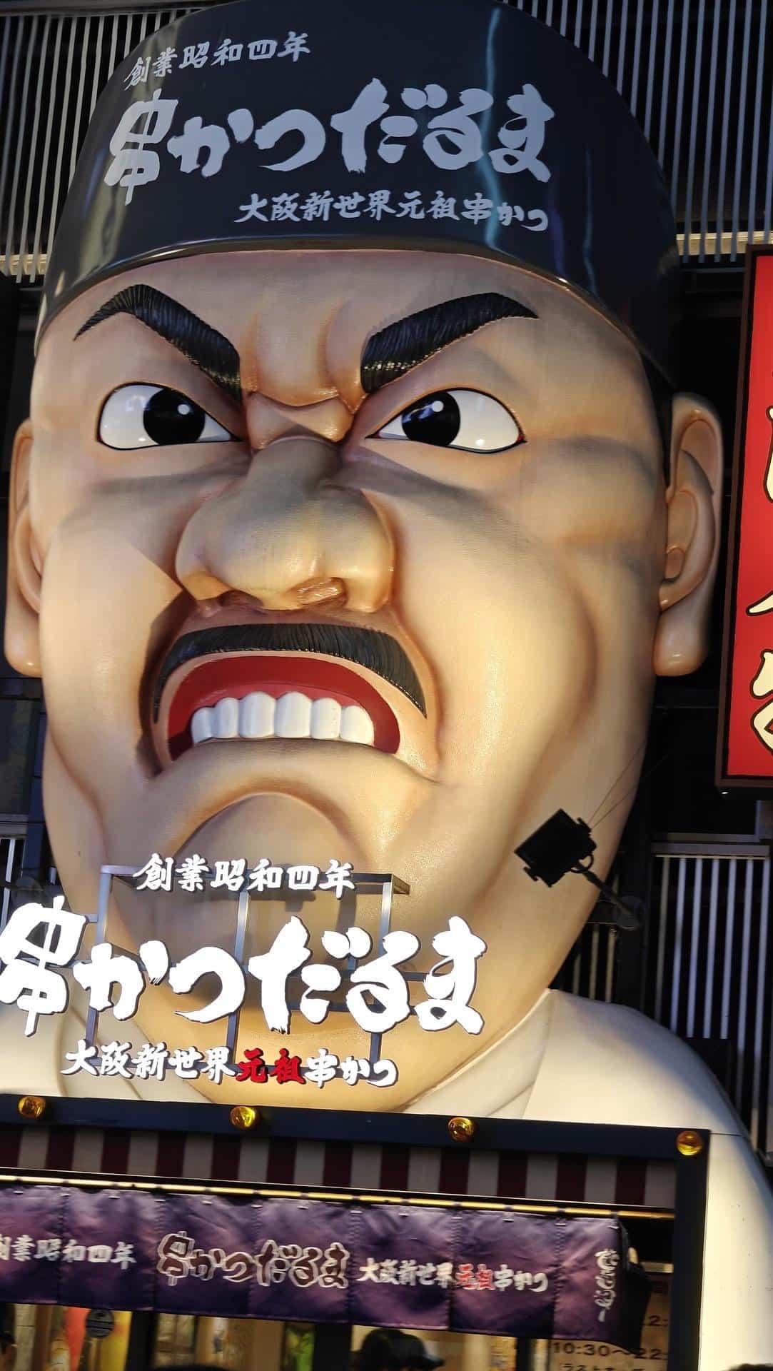 Giant face sign above restaurant entrance