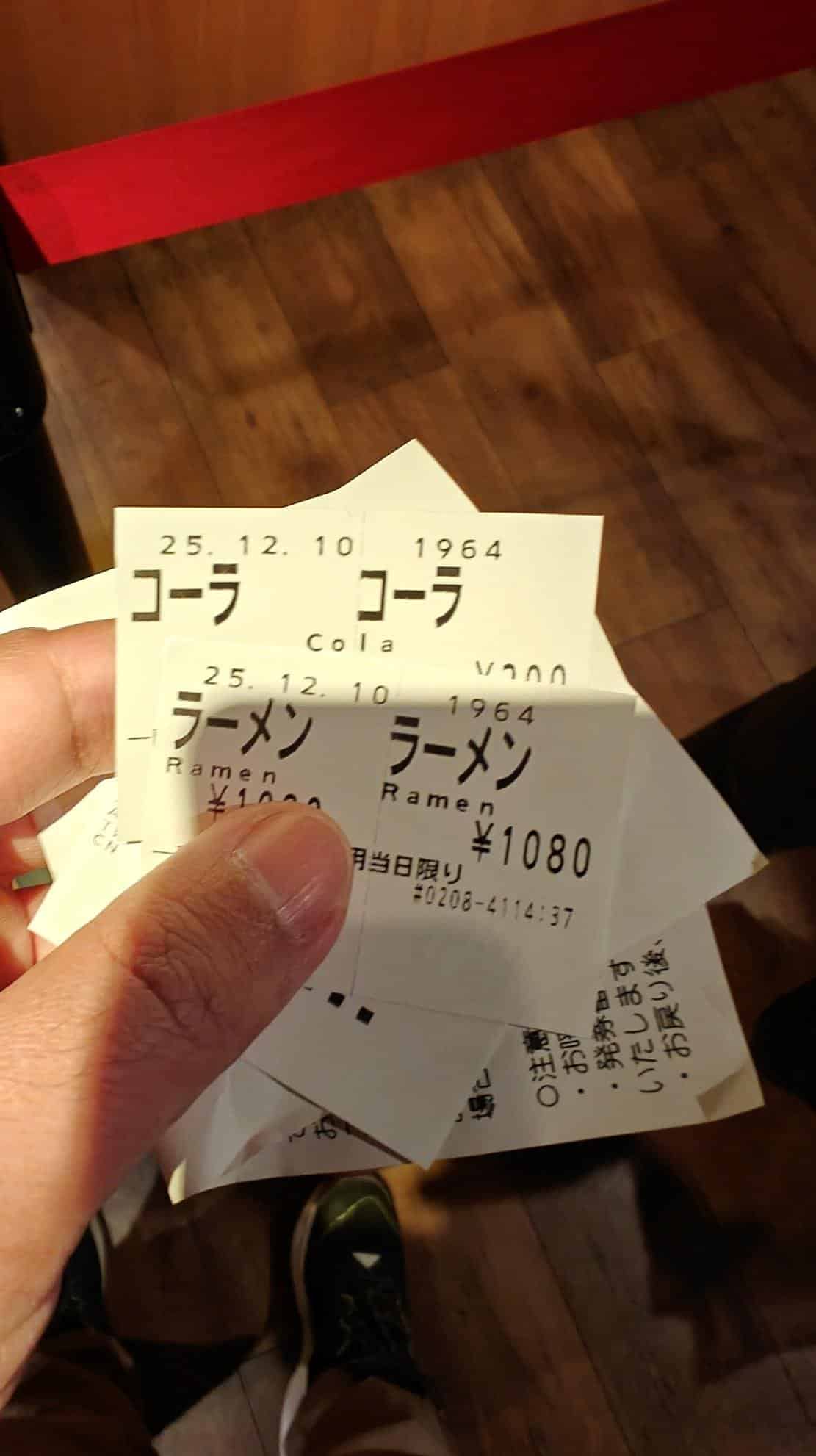 Hand holding ramen and cola tickets