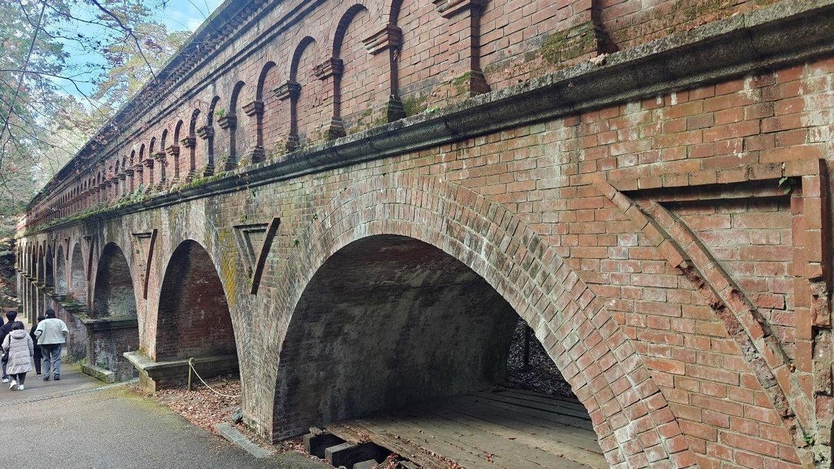 Historic brick aqueduct with arches and people walking nearby